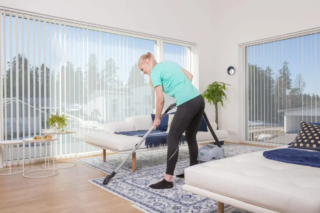 a woman vacuuming a rug in a living room